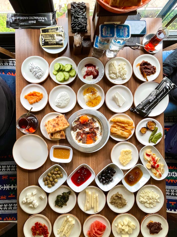 Diverse Turkish breakfast with various small plates set on a wooden table in a cozy setting.